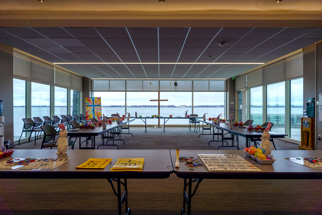 Bayside View Multipurpose room with Easter and cross decorations, bingo boards, and floor-to-ceiling windows with a view of Storm Lake.
