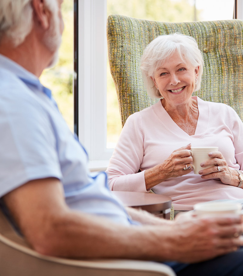 A senior couple sitting in chairs and chatting and relaxing.